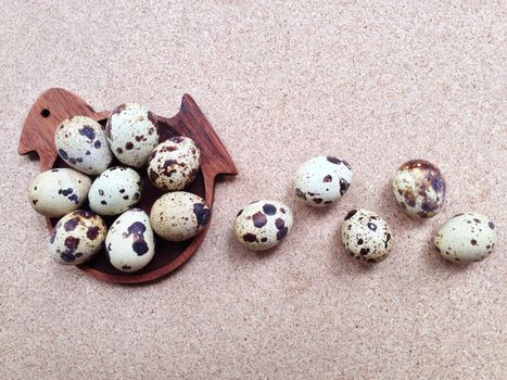 Quail eggs in wooden bird shaped saucer plywood background