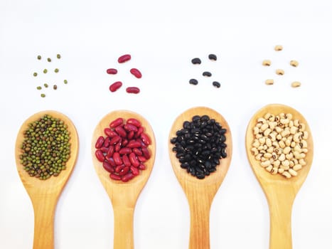 Black eye peas, mung beans, black beans and red kidney beans and wooden ladle on white background