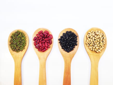 Black eye peas, mung beans, black beans and red kidney beans and wooden ladle on white background