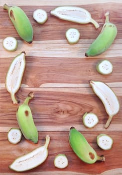 Green cultivated banana and piece of slices on wooden background