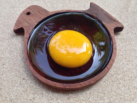 Egg yolk on wooden chicken shaped saucer