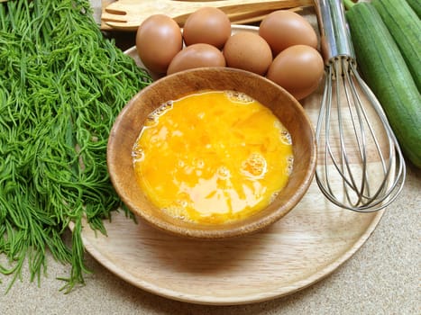 Fresh eggs in wooden bowl with eggs, egg whisk, angle gourd and climbing wattle