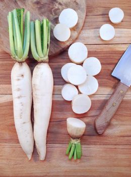 White daikon radish with sliced pieces on wooden table