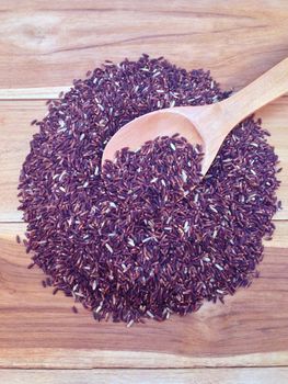 Rice berry with wooden ladle on wooden background