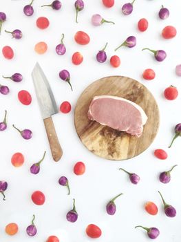 Pork on cutting board with tomatoes and  Thai eggplants