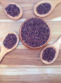 Rice berry in wooden bowl and ladle on wooden background