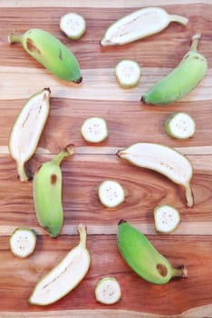 Green cultivated banana and piece of slices on wooden background