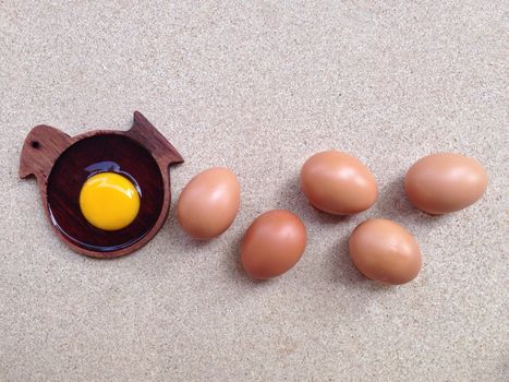 Egg yolk on wooden chicken shaped saucer and eggs on plywood