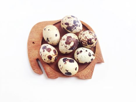 Quail eggs on wooden elephant shaped saucer on white background