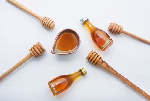 Honey with wooden dipper and little honey bottle on white wooden background.