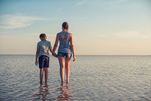 Mother and her son on salty lake with beauty sunset