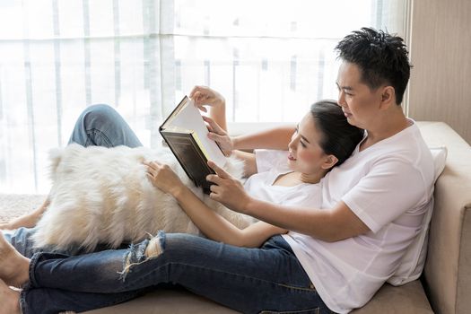 Young Couples reading book tohether in living room of contemporary house for lifestyle concept