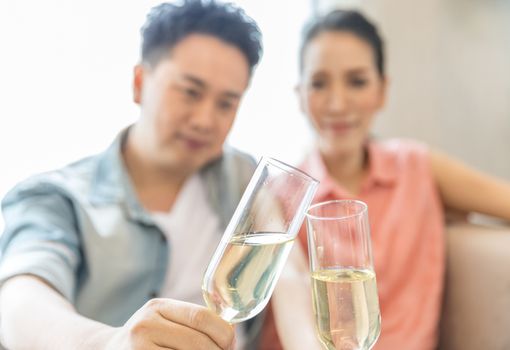 Young Couples celebrate together with wine  in bedroom of contemporary house for modern lifestyle concept (Focus at glasses)