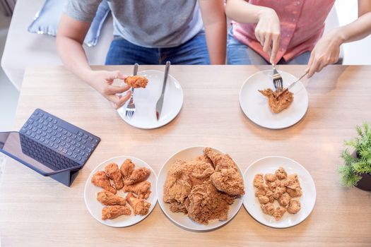 Young Asian Couples eating fried chicken together in living room of contemporary house for modern lifestyle concept Top View