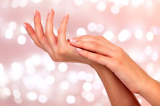 Beautiful and healthy female hands agsainst an abstract background with blurred lights