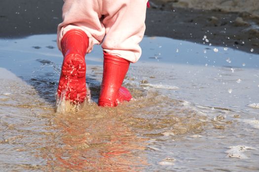 wellingtons in puddle.kid rubber boots in the sea background