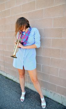 Female jazz trumpet player blowing her horn outside.