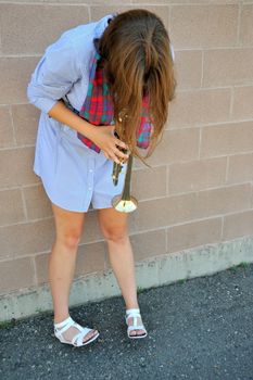 Female jazz trumpet player blowing her horn outside.