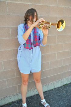 Female jazz trumpet player blowing her horn outside.