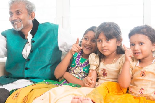 Portrait of Indian family watching tv at home. Happy Asian father and children indoors lifestyle.