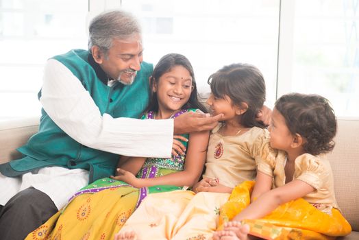 Portrait of happy Indian family sitting at home. Asian father and children indoors lifestyle.