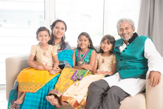 Portrait of happy Indian family in traditional clothes at home, smile at camera. Asian parents and children indoors lifestyle.