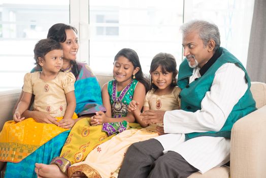 Portrait of happy Indian family talking at home. Asian people indoors lifestyle.