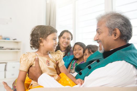 Portrait of happy Indian family sitting on couch at home. Asian people indoors lifestyle.