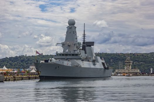 Military navy ship in port. Military sea landscape with cloudy sky.