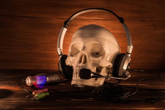 Skull with headphones on an old wooden background. A human skull lit by candles on  wooden floor, the concept of Halloween.