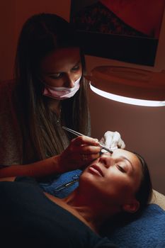 Beautician applying permanent makeup for eyebrows to model.  