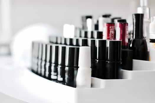 Black small bottles with nails lacquer on the white holder in SPA salon.