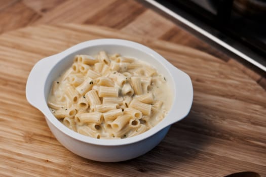 Delicious and fresh pasta on white plate on wooden board in the kitchen. Cooking concept.