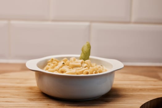 Delicious and fresh pasta on white plate on wooden board in the kitchen. Cooking concept.