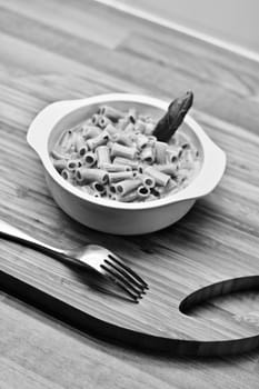 Delicious and fresh pasta on white plate on wooden board in the kitchen. Cooking concept.