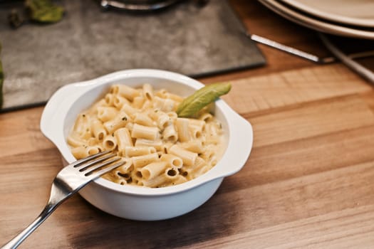 Delicious and fresh pasta on white plate on wooden board in the kitchen. Cooking concept.
