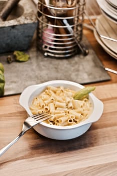 Delicious and fresh pasta on white plate on wooden board in the kitchen. Cooking concept.