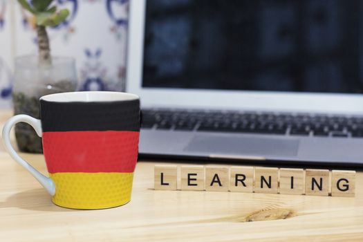 Germany  flag painted on cup coffee, letter wood learning,gray laptop