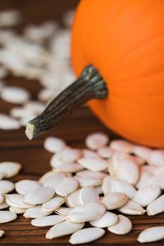 Fresh orange pumpkin and pimpkin seeds close-up on wooden background