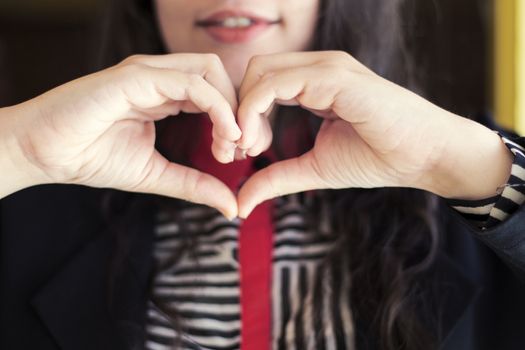 muslim business woman with smiley beautiful lips making heart shape by her hands