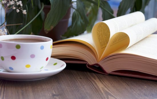 Heart shape made from book pages and drinking coffee