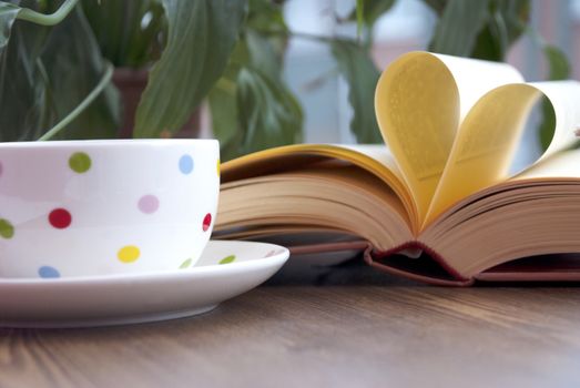 Heart shape made from book pages and drinking coffee