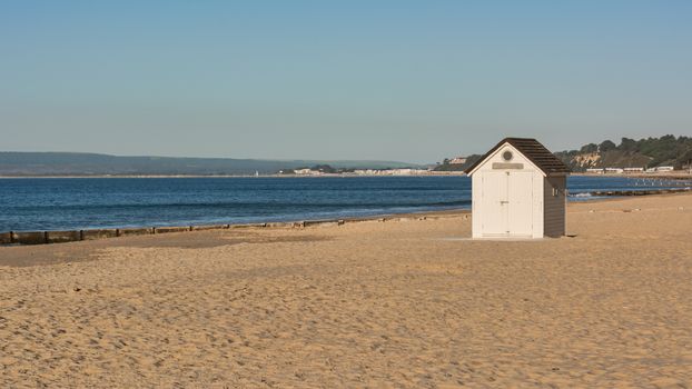 A single isolated beach hut on the deserted shore coast of Bournemouth in the UK.