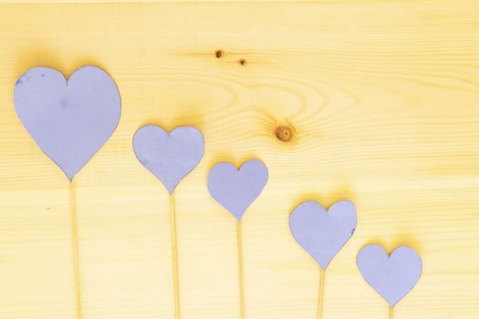 four blue heart paper with wooden stick on wood table