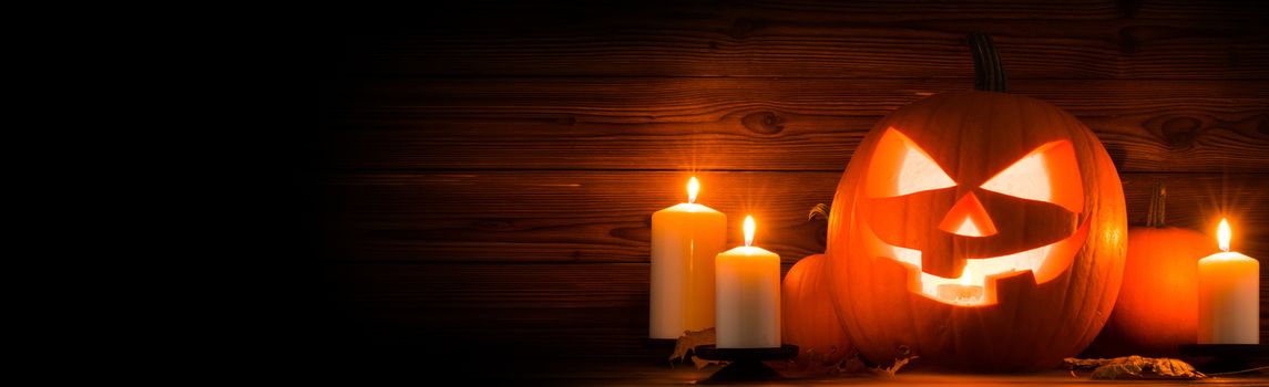 Halloween pumpkin head jack lantern and candles on wooden background