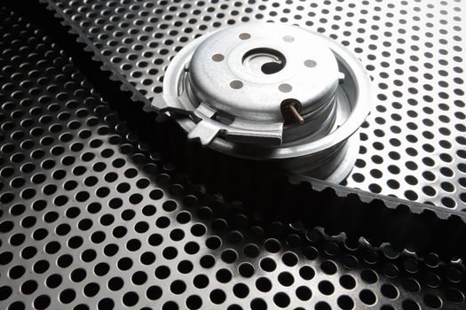 Bearing tensioner and timing belt on a metal surface. Photo from the vignetting effect