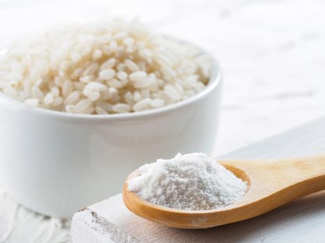 rice flour in wooden spoon and rice grains on white background