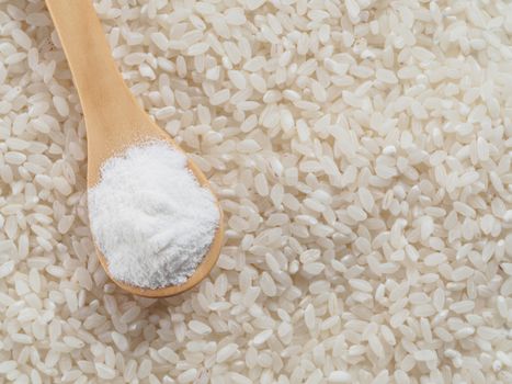 rice flour in wooden spoon and rice grains. whole-grain rice flour on rice grains background. Copy space. Top view or flat lay.