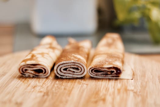 Delicious and fresh pancakes with strawberry sauce on the wooden board in the kitchen.