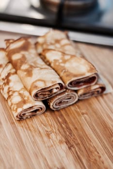 Delicious and fresh pancakes with strawberry sauce on the wooden board in the kitchen.